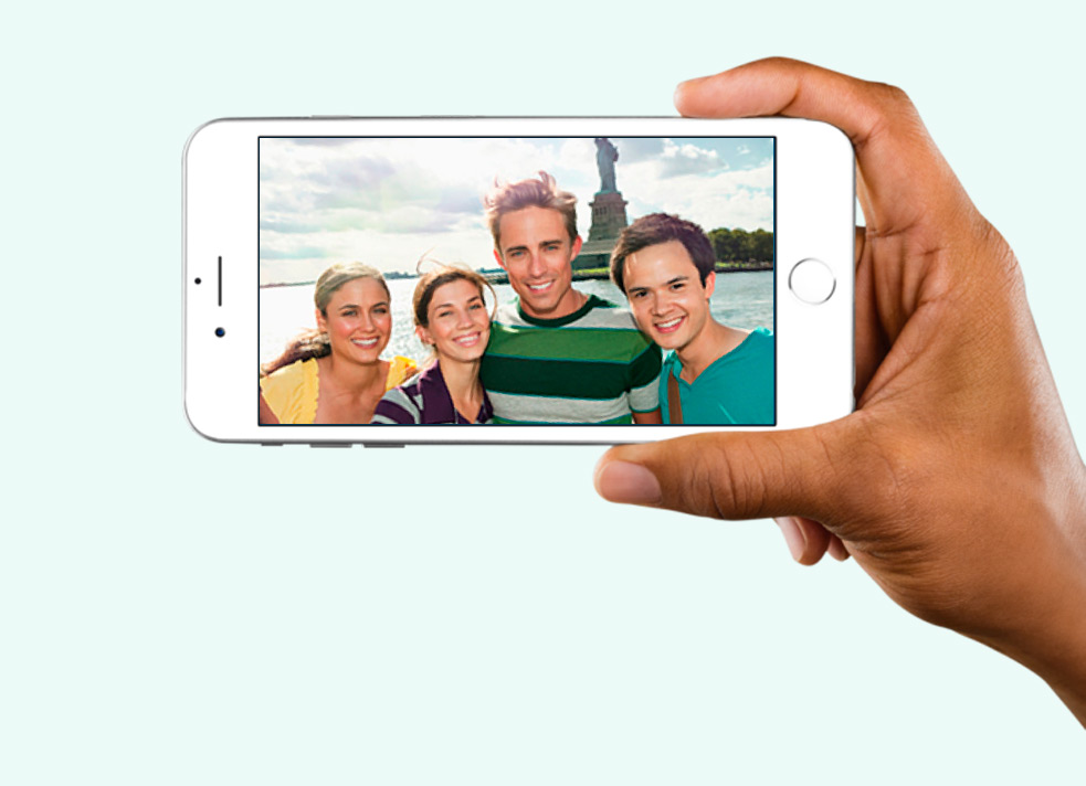 handing holding iphone with photo of friends at statue of liberty