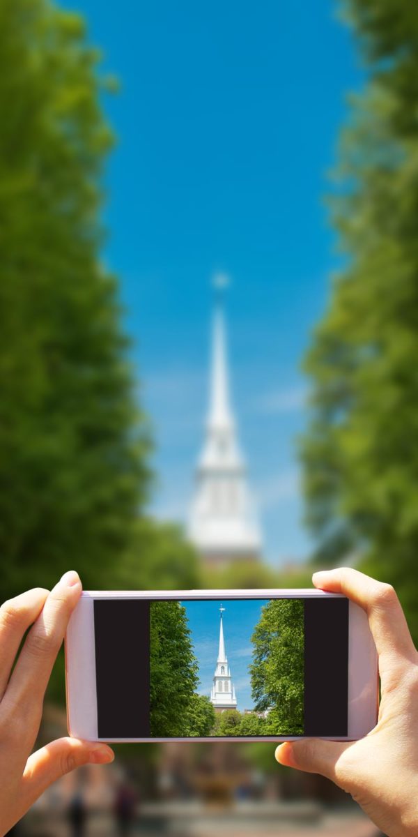 Hands holding a phone to take a picture of monument on a sunny day